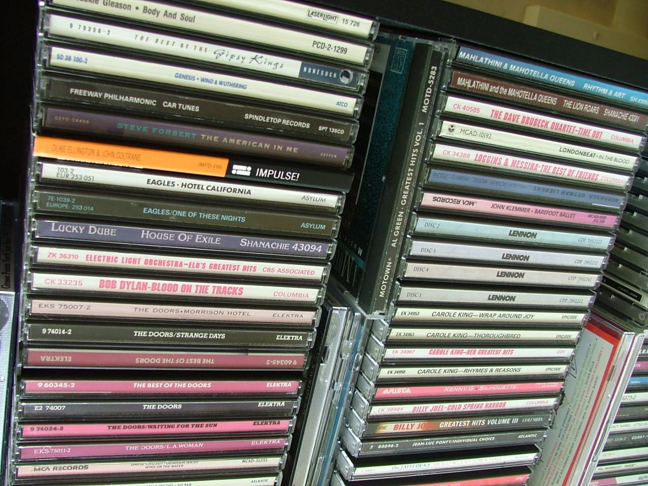 A rack of CDs, the format Napster made briefly optional. Photo: Arbitrarily0, Wikimedia Commons, CC BY-SA 3.0.