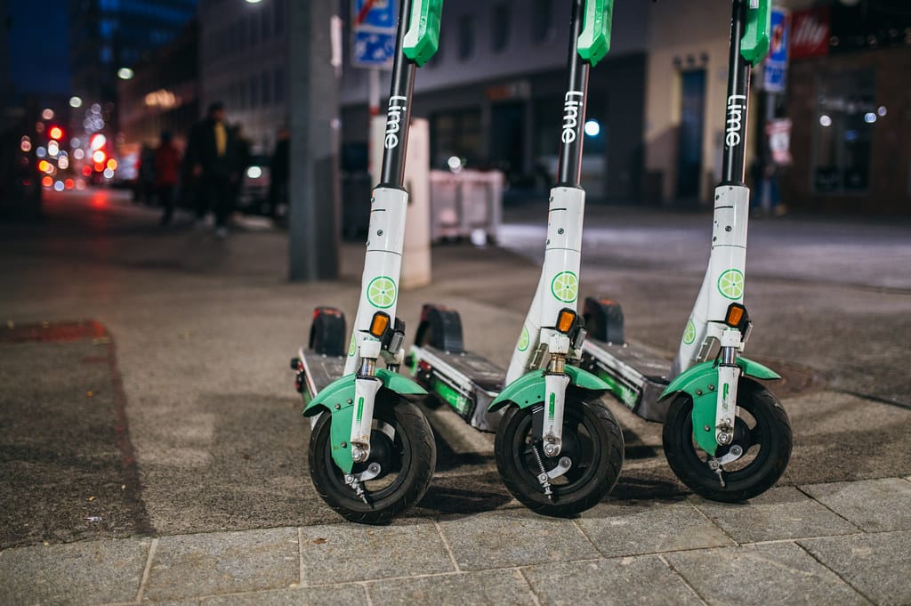 Rental e-scooters parked on a city sidewalk at night